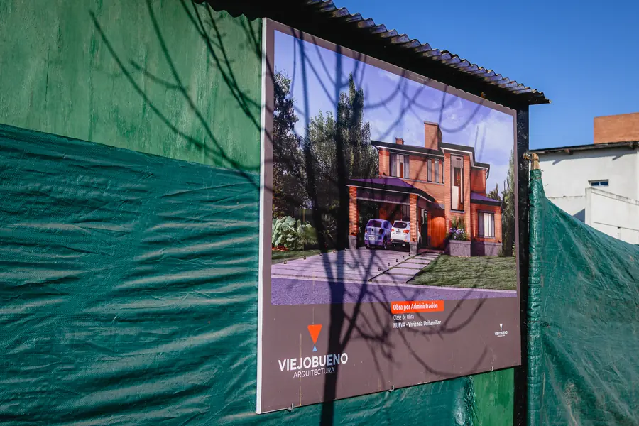Cartel de obra de Viejobueno Arquitectura con el render de la casa, sobre el cerco